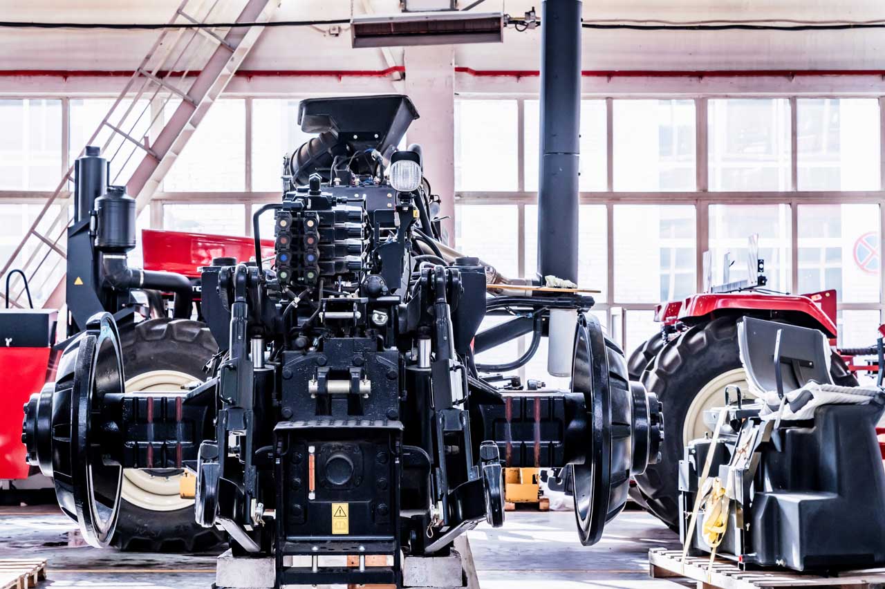 A large tractor is assembled inside a modern factory.