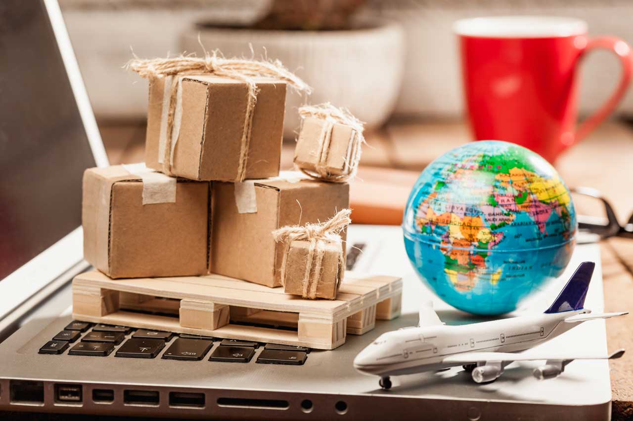 global-shipping Scale model boxes, wood pallet, aircraft and world globe sit on a laptop.