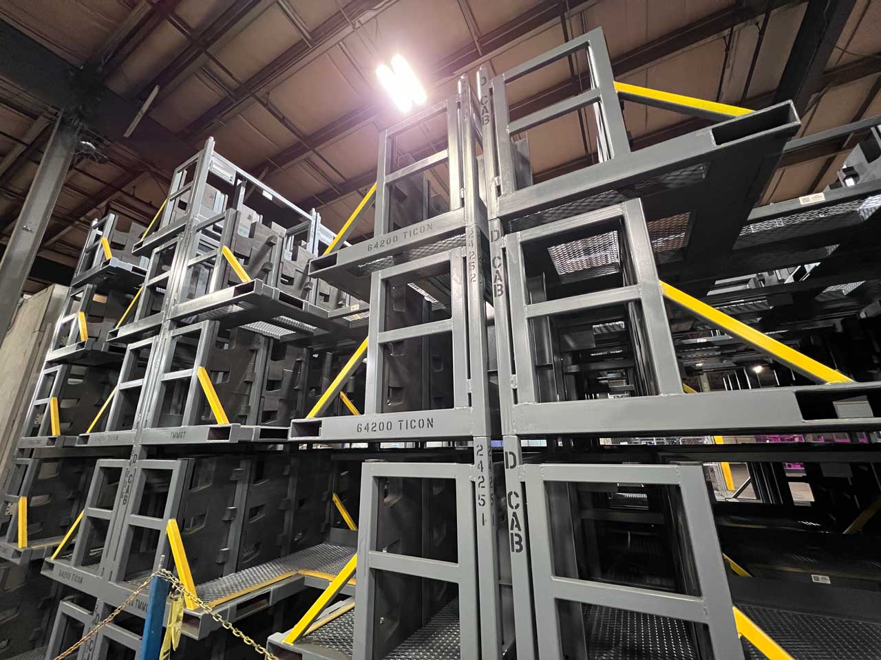 tall-stacked-racks Steel rectangular racks are stacked high inside a manufacturing facility.