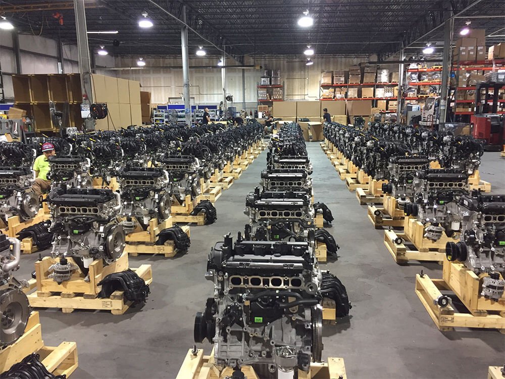 engine-skids Rows of automotive engines on wooden pallets inside an industrial facility.