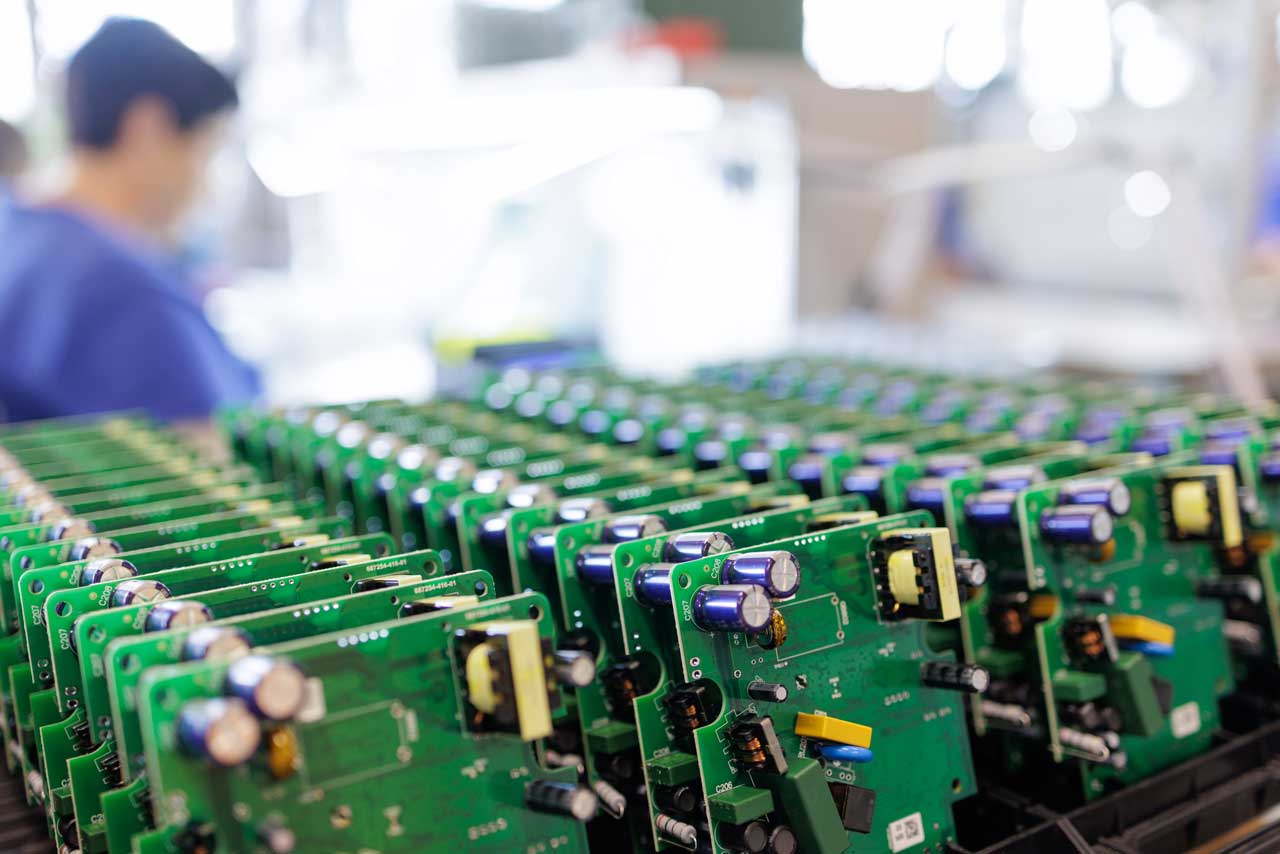 Rows of electronics circuit boards are arranged in a tray at a manufacturing facility.